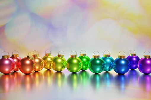 3d render of beautiful metallic rainbow xmas baubles on a colorful bokeh background for your festive Christmas project