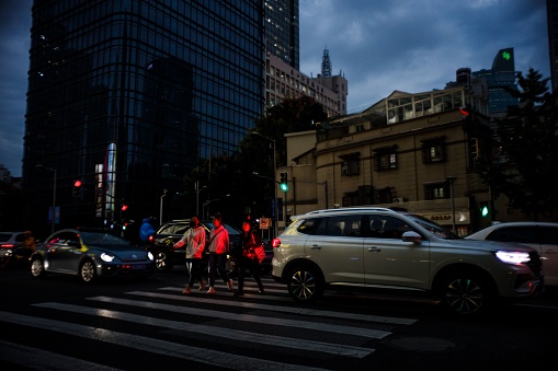 Shanghai, China – October 19, 2021: A night view of a street with people on a pedestrian crossing