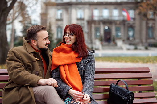 Young couple in love sitting on bench in the city after walk