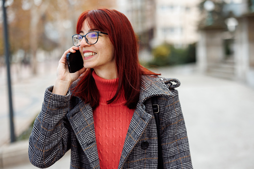 Portrait of happy young woman talking on the mobile phone outdoors