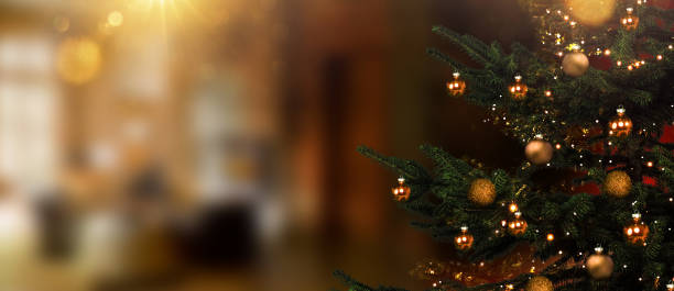 Christmas tree in foreground against blurred living room in background stock photo