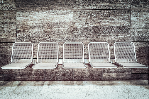 An empty row of modern metal seats in a subway station.