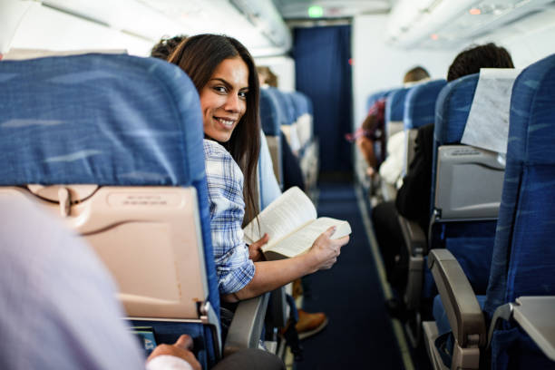 istock Happy woman reading a book in an airplane. 1445672586