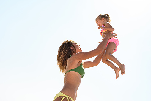 Carefree mother and daughter having fun during summer day against the sky. Copy space.