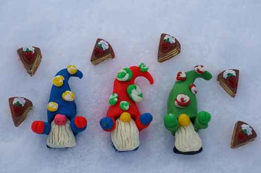 Three fabulous dwarfs with treats on a background of snow.