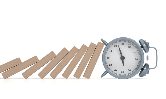 Alarm Clock stopping wooden domino. Risk Management Concept.