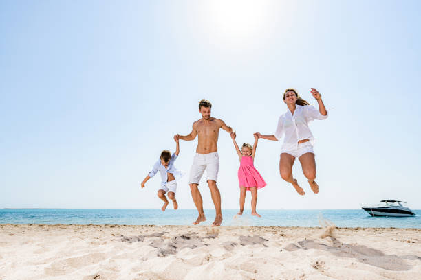 istock Playful family having fun while jumping on the beach. 1445673995
