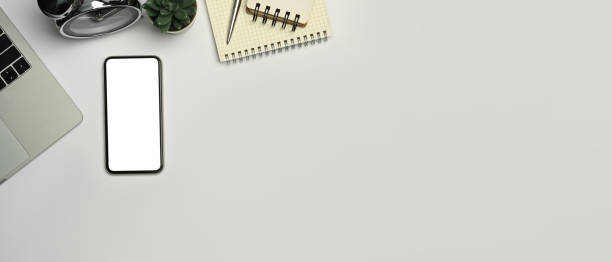 istock Top view of mobile phone, notepad, potted plant and coffee cup on modern workspace. Blank screen and copy space for your advertise. 1445675251