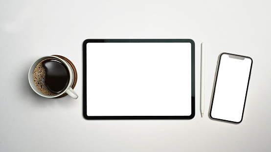 Digital tablet, smart phone, stylus pen and cup of coffee on white background. Empty screen for advertise design.