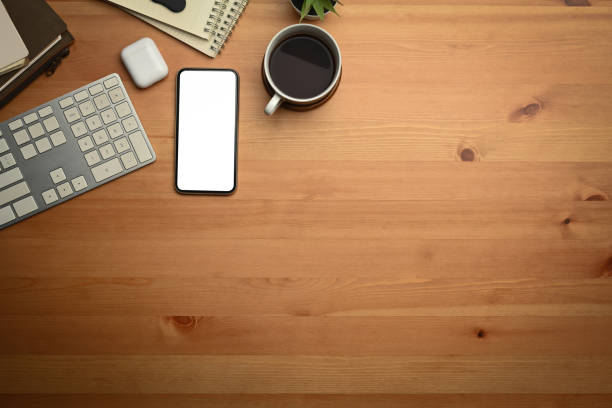istock Top view of mobile phone, notepad, potted plant and coffee cup on modern workspace. Blank screen and copy space for your advertise. 1445675338
