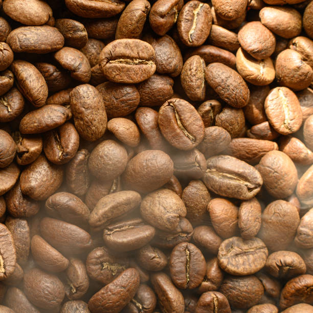 Black coffee beans with a slight haze from the steam, the texture of coffee beans.