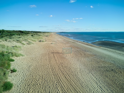 Aerial, drone summer image over Östra Stranden, Beach region in Halmstad, Halland, Sweden. Image captured on a sunny day shows a sandy beach with almost no people. Blue sea, blue water and sky. Idyllic holiday destination.