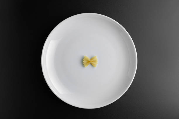 istock Raw pasta farfalle on plate on black background. 1445676252