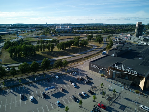 Halmstad, Halland, Sweden - 08.30.2022: Aerial, drone image over shopping mall Hallarna. Image shows building and nearby infrastructure, parking lots, motorway. Popular place. Summer weather. Scenic. Big parking space. Modern architecture exterior. Location that is often popular in discussions.