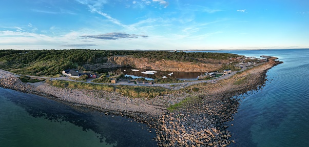 Grötvik, Halmstad, Halland, Sweden - 08.30.2022: Aerial drone image that presents a small boats harbour, port and old quarry at the west coast of Sweden. Location is popular during holidays due to a pure water, blue sky and many activities. Idyllic coastal landscape in a panoramic view. No recognizable people. Popular travel destination.
