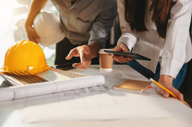 istock Creative architect projecting on the big drawings in the dark loft office or cafe in morning light 1445679108