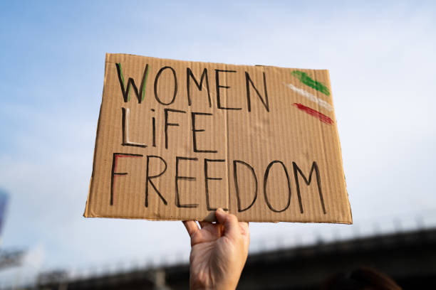 Demonstrator holding "Women, Life, Freedom" placard Demonstrator holding "Women, Life, Freedom" placard iranian ethnicity stock pictures, royalty-free photos & images