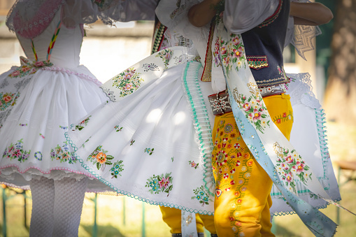 Deva, Romania - 16 July, 2021: a group of young traditional Romanian dancers wearing the traditional white costumes with intricate embroidery. They have just performed in a local park.