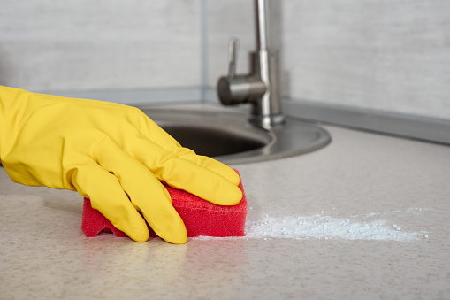 Deep Cleaning service. woman gloves hands cleaning kitchen table with red sponge. Surface sanitizing. Home cleaning and disinfecting. wearing nitrile gloves.