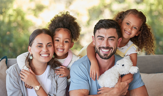 Family, mother and father with foster children hugging in a happy portrait together love sharing quality time together. Girls, dad and mom are proud adoption parents of cute kids enjoying the weekend