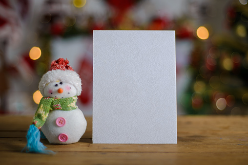 Blank Christmas card next to ornament on wooden table, Christmas background blurred. Christmas card mockup.