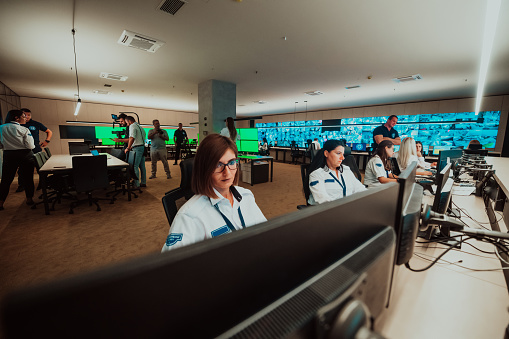group of female security operators working in a data system control room Technical Operators Working at the workstation with multiple displays, security guards working on multiple monitors in