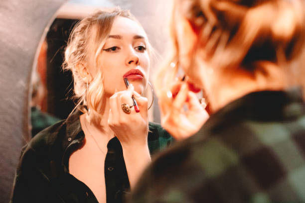 istock Young woman using lip pencil while drawing contours applying lipstick doing make up at home getting ready to go out 1445688669