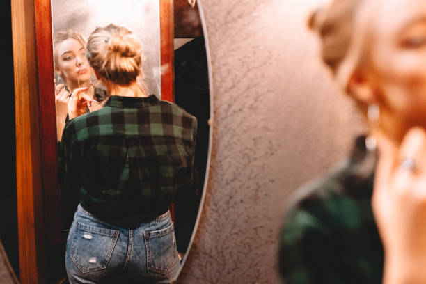 istock Young woman looking at herself in the mirror while standing in hallway at home getting ready before going out 1445688684