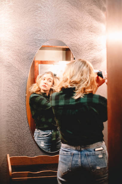 istock Young woman using curling iron looking at herself in the mirror at home getting ready to go out 1445688755