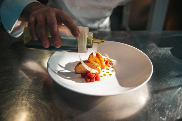 Young chef plating and finalizing food in a fine dining luxury restaurant.