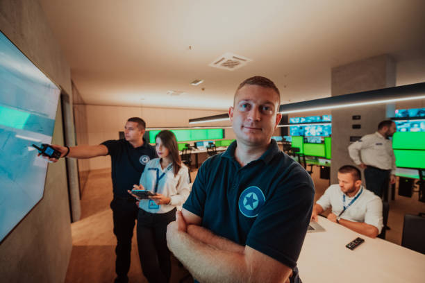 istock Group of Security data center operators working in a CCTV monitoring room looking on multiple monitors Officers Monitoring Multiple Screens for Suspicious Activities Team working on the System Contr 1445691429
