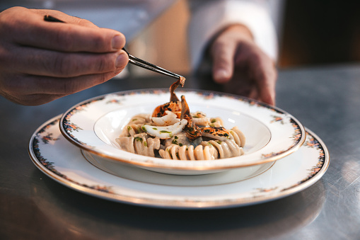 Chef preparing Fusilli pasta plate in a luxury restaurant. Close up view.