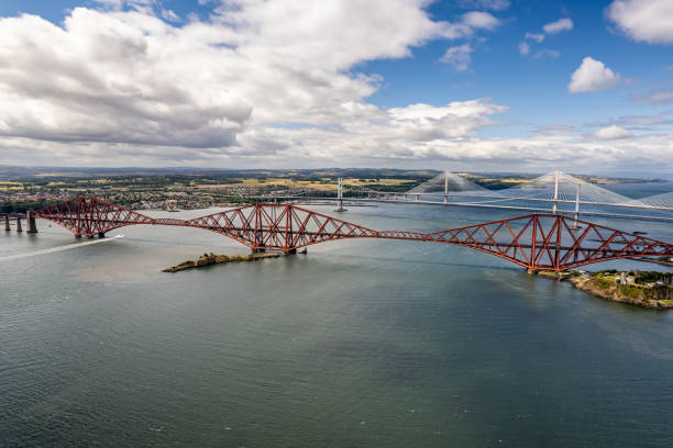 The drone aerial view of the Forth Bridges and the new Queensferry Crossing. The world's first major steel structure, the Forth Bridge represents a key milestone in the history of modern railway civil engineering and still holds the record as the world's longest cantilever bridge. bridge crossing cloud built structure stock pictures, royalty-free photos & images