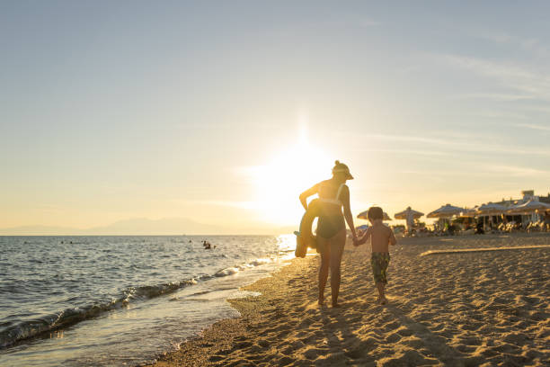 istock Mother and son walking together on the beach 1445692335