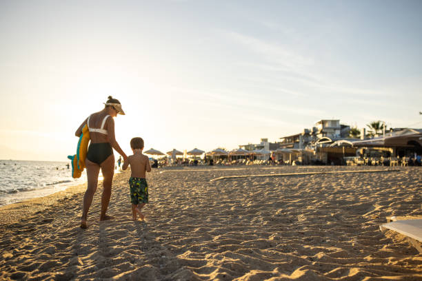 istock Mother and son walking together on the beach 1445692381