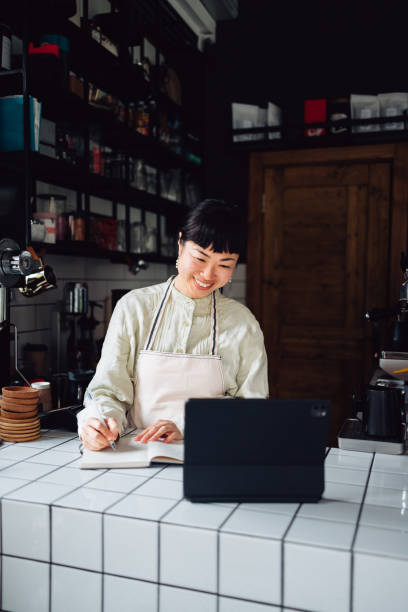 istock Smiling Female Employee Using A Digital Tablet While Working In A Coffee Shop 1445692583