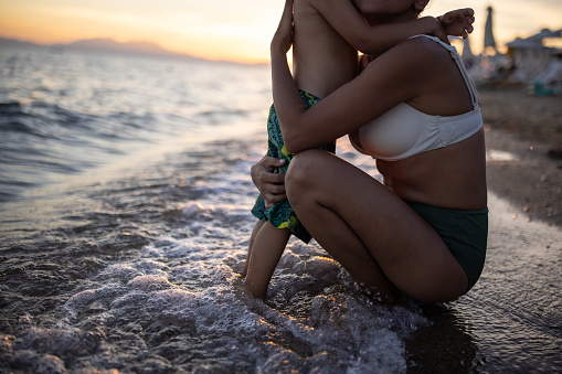 Mother and son playfully embracing on the beach