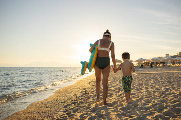 istock Mother and son walking together on the beach 1445693318