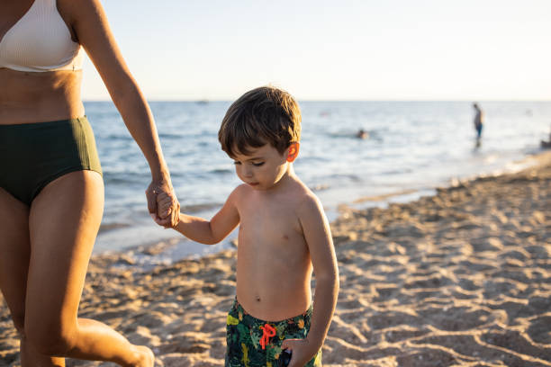 istock Mother and son walking together on the beach 1445693321