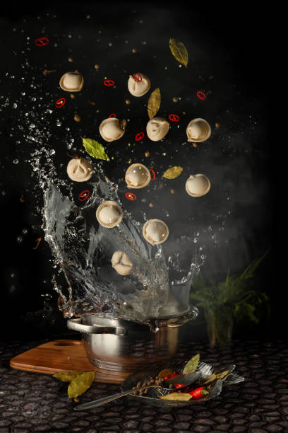 der prozess der herstellung von pasta und ravioli. knödel mit gewürzen in heißem wasser auf schwarzem hintergrund. kunst food fotografie - foodstyling stock-fotos und bilder