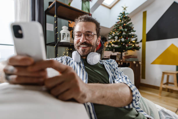 istock Young man using a phone at home in a New Year's atmosphere 1445696745