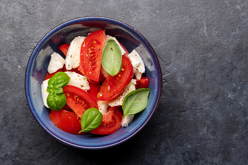 Caprese salad with ripe tomatoes, mozzarella cheese and garden basil. Flat lay with copy space
