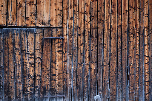 A pair of rusty padlocks secure the weathered doors of a rustic cranberry barn on Cape Cod.