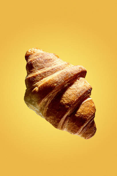 A poster with a levitating croissant on a yellow background. Freshly baked croissant for breakfast. Creative flying food poster. Baking