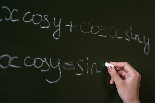 female teacher writing math formulas, cos and sin. education concept
