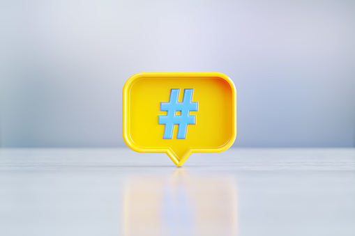Yellow speech bubble with blue hashtag symbol sitting on before silver defocused background. Horizontal composition with copy space.