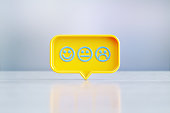 Yellow Speech Bubble Shape With Blue Face Emojis Sitting Before Silver Defocused Background