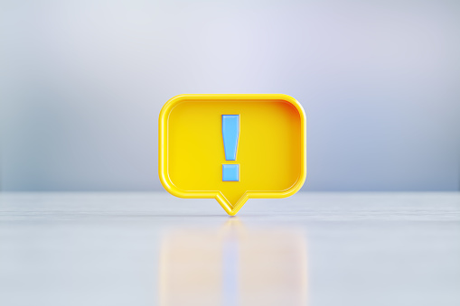 Yellow speech bubble with blue exclamation point sitting on before silver defocused background. Horizontal composition with copy space.