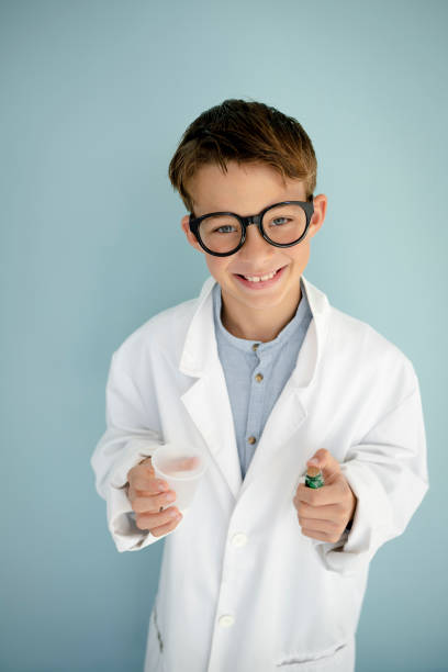 istock young cool boy ,with big massive black glasses is dressed up as a mad scientist holding beaker and vials in hand 1445706886