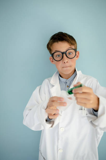 istock young cool boy ,with big massive black glasses is dressed up as a mad scientist holding beaker and vials in hand 1445706919